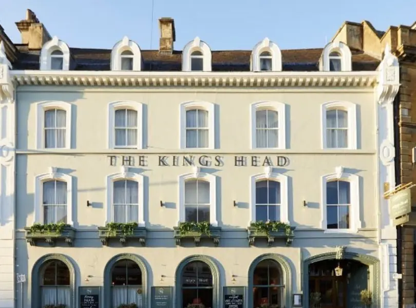 The Kings Head hotel in Cirencester, a cream-painted Georgian frontage with arched ground-floor windows.