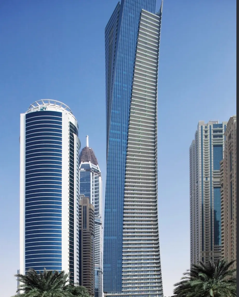 Residential high-rise towers in Dubai rising against a clear blue sky.